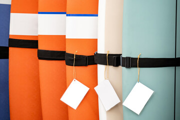 Empty price tag hanging on colorful surfboard display for sale in water sport equipment store.