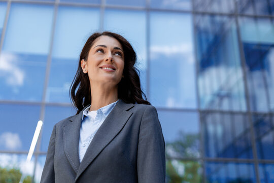 Businesswoman smiling and looking up in front of modern office building