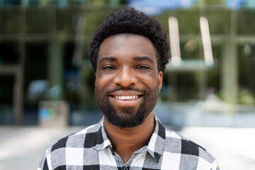 Portrait of smiling young african american businessman standing outside modern office building