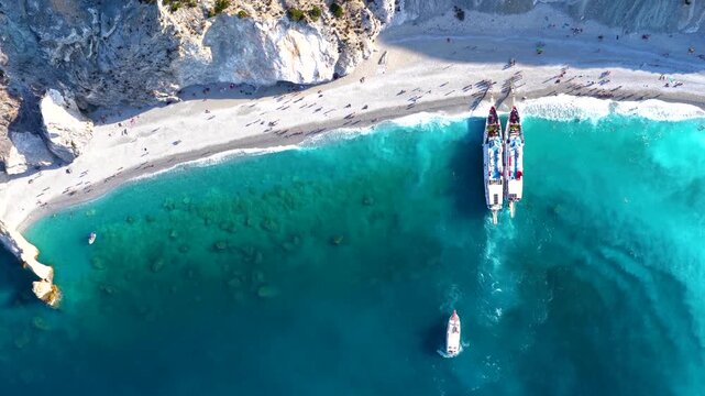 Aerial overhead view of the beautiful beach at Lalaria, Skiathos island, Sporades, Greece, with excursion boats and people enjoying the sunset