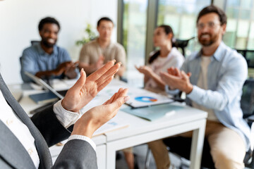 Businesswoman receiving applause from colleagues after successful presentation