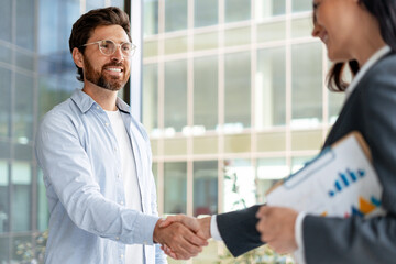 Businessman and businesswoman shaking hands in modern office building
