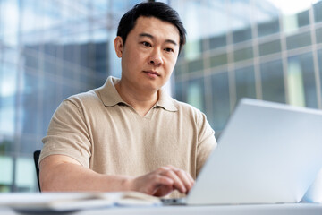 Asian businessman working on laptop in modern office