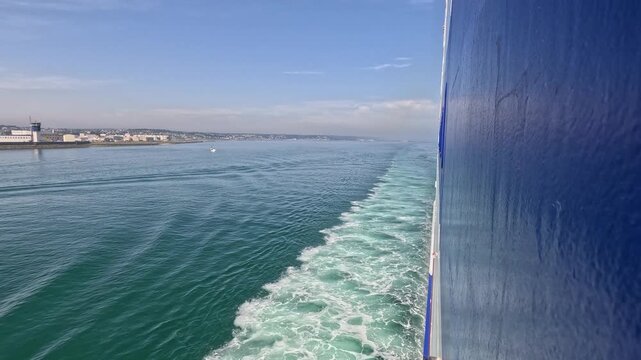 Steel hull of huge transport ferry leaves wake in ocean, leaving port