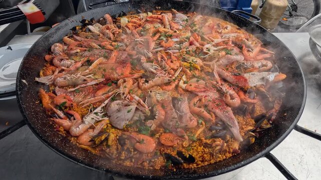 Enormous discada wok cooks paella on street with rice and seafood