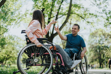 Two individuals in wheelchairs sharing a joyful moment outdoors, demonstrating friendship, support, and inclusion in a natural and beautiful setting.