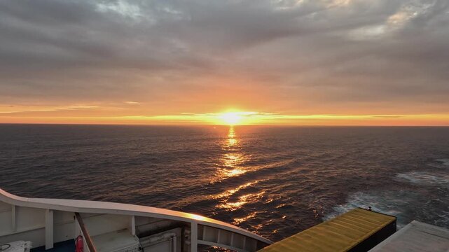 Golden sunset horizon in calm ocean from deck of large transport ferry