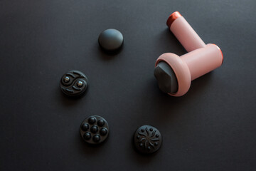 Pink massage gun with soft head and four different black attachments arranged on dark background....