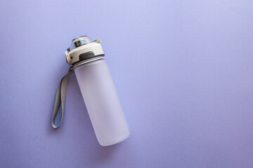 Minimalist sports water bottle with carrying strap and flip-top lid on a light purple background. Frosted plastic design for fitness, hydration, and daily use