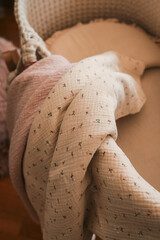 Soft pastel pink and beige muslin blankets with delicate floral patterns layered inside a cozy...