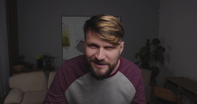 Close-up of a funny, bearded guy looking into the camera, a mirror, or a window,and smiling maliciously at what he sees