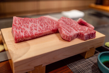 Raw A5 Kobe beef with intense marbling presented on a wooden board at a Japanese teppanyaki...