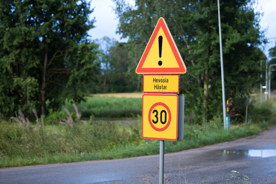 Finnish road sign warning of horses on the road with speed limit in rural countryside