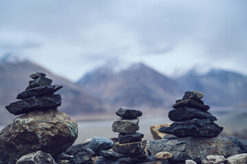 Balanced stacked stones in Ladakh with blurred Himalayan mountain backdrop symbolizing harmony and mindfulness