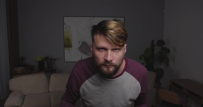 Close-up of a bearded blond man crying funny, standing in a room at home. there are a lot of tears, and he wipes them away with his hand