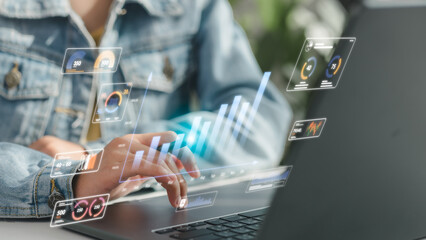 Close-up of person using laptop with holographic analytics dashboard showing business charts, KPI...
