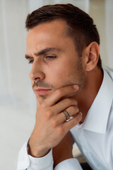Pensive man wearing striped ring in white shirt close-up