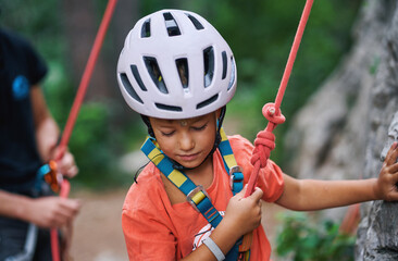 Young child with helmet and harness preparing for outdoor rock climbing