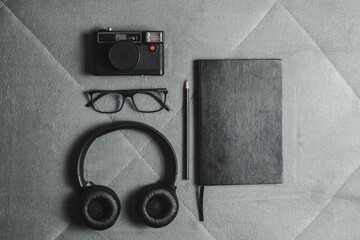 Flat lay of camera, glasses, headphones, and notebook.