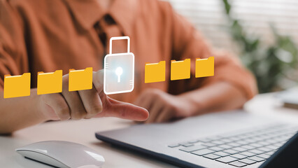 User tapping on virtual lock icon among file folders on laptop, symbolizing secure file access,...