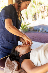 Massage therapist performing relaxing face massage outdoors
