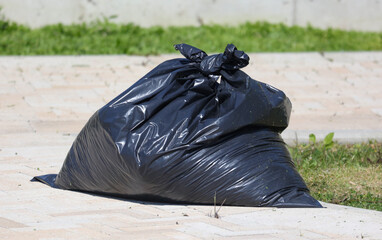 A black trash bag is sitting on the ground