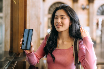 Chinese woman waits at the train station while checking her phone and enjoying her surroundings...