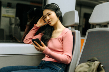 Chinese woman enjoys music while traveling on a train, immersed in her own world and capturing...