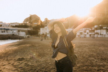 Joyful Chinese woman enjoying a sunny day at the beach while embracing the warm sunlight