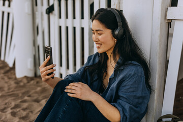 Woman enjoying nature while listening to music on her phone near a beach