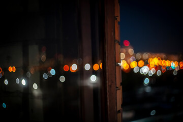 Night city lights. Night view from a window with colorful bokeh city lights creating a dreamy...