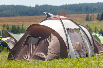 A large tent is set up in a field with other tents in the background