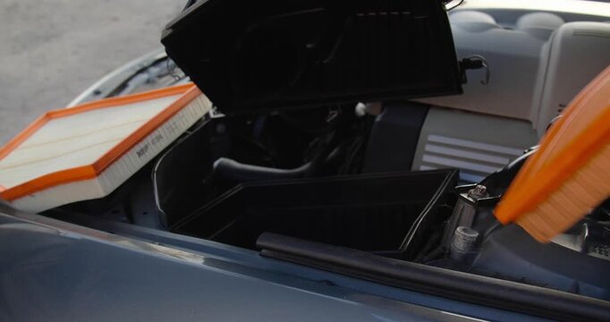  Male hands in gloves changing the air filter in a car. Taking care of the engine compartment