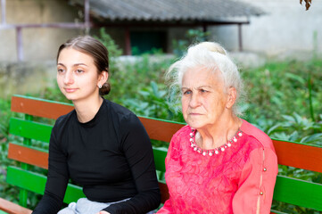 Two generations share a quiet moment on a colorful bench in an outdoor garden, reflecting on...