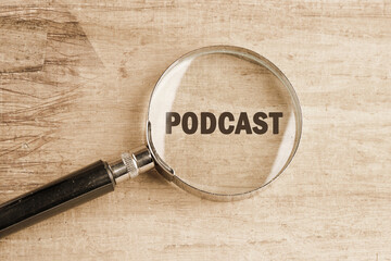 A magnifying glass emphasizes the word podcast on a wooden surface, representing the exploration of...