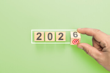 Hand completing 2026 new year business goals. Man putting last wooden block with target icon in...