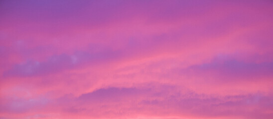 serene sunset over the sea with the sun partially hidden by clouds, creating a beautiful pink and purple sky