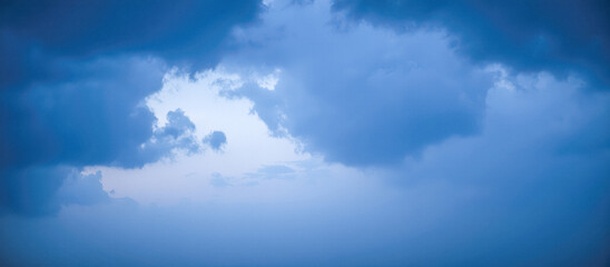 Obraz premium Hole of clear light in dark blue stormy clouds, atmospheric sky background symbolizing hope, freedom, or wonderful new beginning