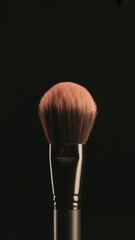 Closeup of a professional makeup brush with soft bristles on black background