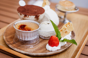 dessert with strawberry ice-cream and cream, tiramisu with cocoa powder, mint leaf, toufu cake roll, biscuit and creme brulee