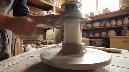 Hands shaping clay on a spinning pottery wheel in workshop, showcasing artisan craftsmanship - Powered by Adobe