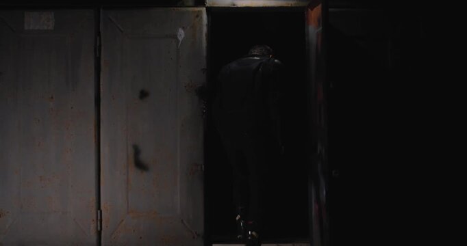 Kyiv, Ukraine 24.08.2023  View of the garage at night through the opened door. A guy in motorcycle gear puts on a helmet, gets on a motorcycle and  ready to ride, turning on the headlight