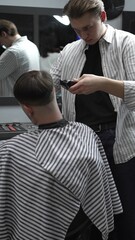 Professional barber carefully trimming customer's hair with electric clipper, providing a stylish...