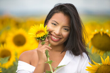 A beautiful mulatto Latin woman with a white shirt brings it close to her face and flirts with a...