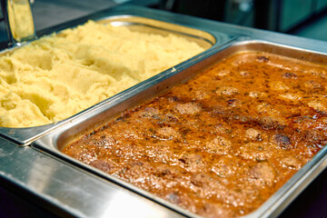 A Delicious Spread of Creamy Mashed Potatoes Paired with Flavorful Beef Meatballs in Rich Gravy for...