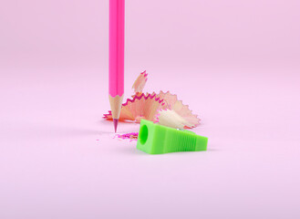 Pink pencil and green sharpener on a pastel pink background.
