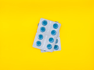 A blue pill is sitting on a white background. The pill is square in shape and has a blue center....