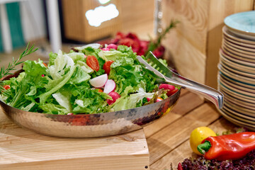 A Fresh Salad Composition, Featuring Crisp Greens and Vibrant Vegetables in a Stylish Serving Bowl Placed on a Rustic Wooden Surface