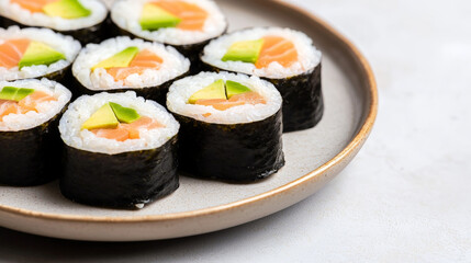 Fresh sushi rolls with salmon, avocado, and rice wrapped in seaweed on ceramic plate, offering healthy and fit meal option for those who enjoy eating fresh and nutritious food
