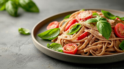 Plate of whole grain pasta topped with fresh basil, cherry tomatoes, and grated cheese, offering healthy and fresh meal option that is both delicious and fit for balanced diet